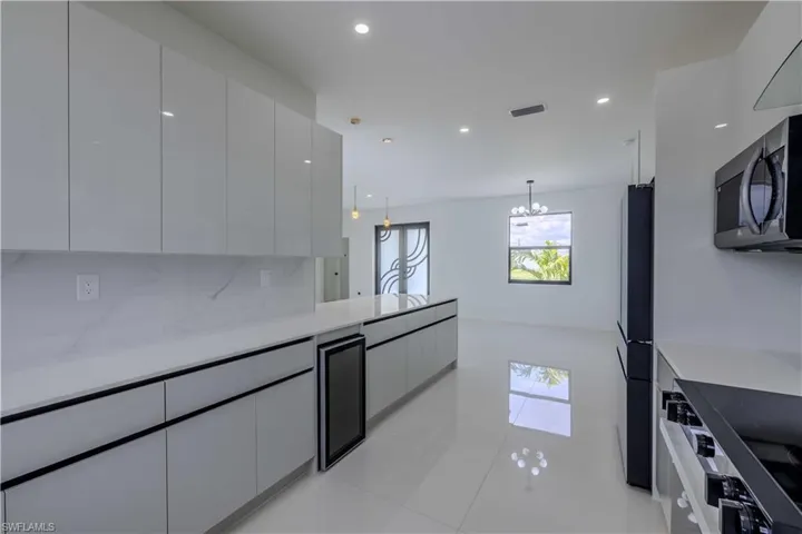 Kitchen with stainless steel microwave, modern cabinets, range with electric cooktop, beverage cooler, and recessed lighting