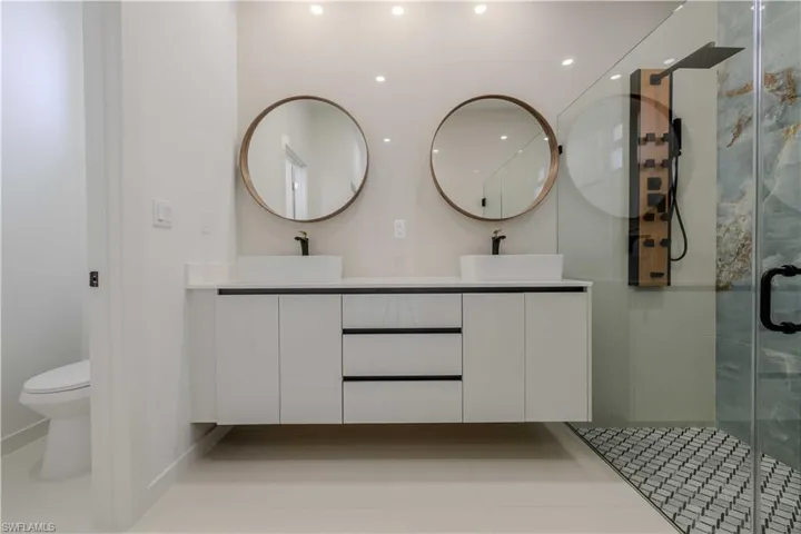 Full bathroom featuring double vanity, a shower stall, and recessed lighting