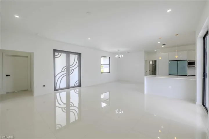Empty room with light tile patterned floors, a chandelier, and recessed lighting