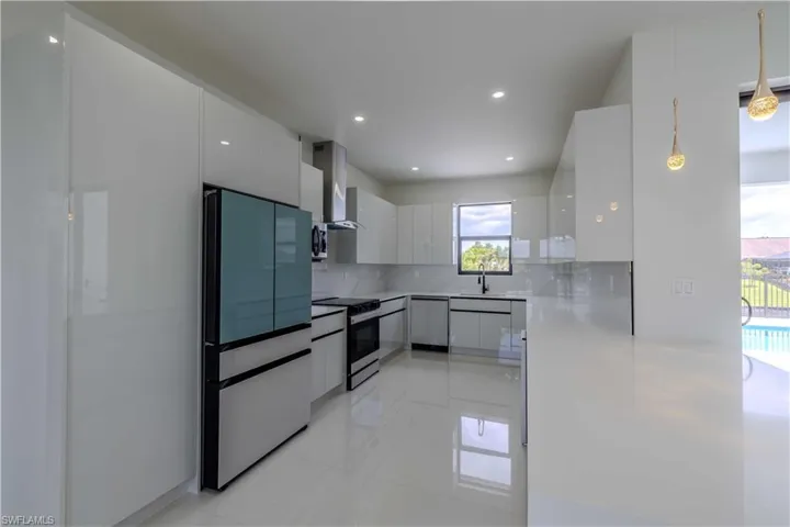 Kitchen with modern cabinets, stainless steel appliances, wall chimney exhaust hood, white cabinetry, and recessed lighting