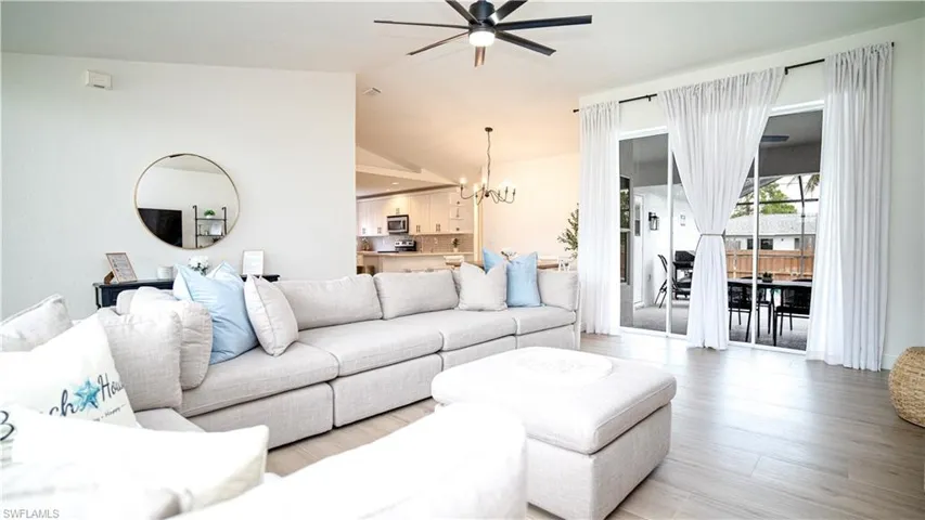 Living room with vaulted ceiling, a chandelier, wood finished floors, and ceiling fan