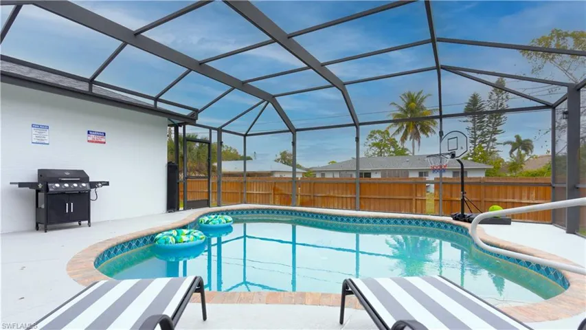 View of pool featuring a fenced backyard, a lanai, a sunroom, a grill, and a patio area