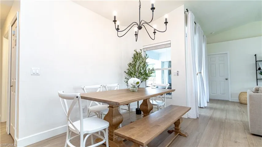 Dining room with light wood-type flooring, a chandelier, and vaulted ceiling