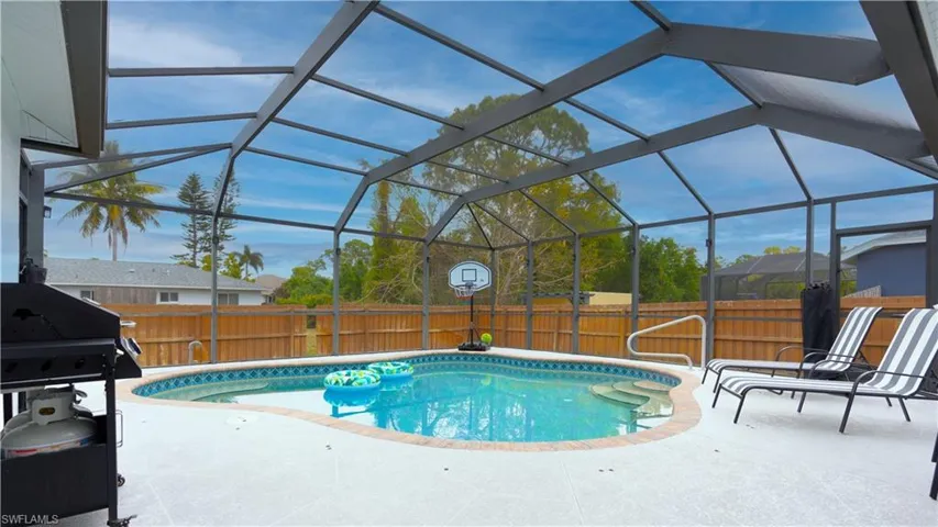 View of pool with area for grilling, a lanai, a fenced backyard, and a sunroom