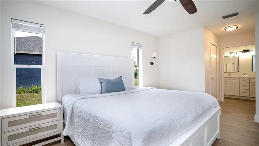 Bedroom featuring light wood-type flooring, ensuite bath, and ceiling fan
