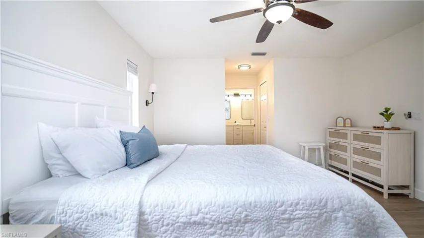 Bedroom featuring wood finished floors, ceiling fan, and ensuite bathroom