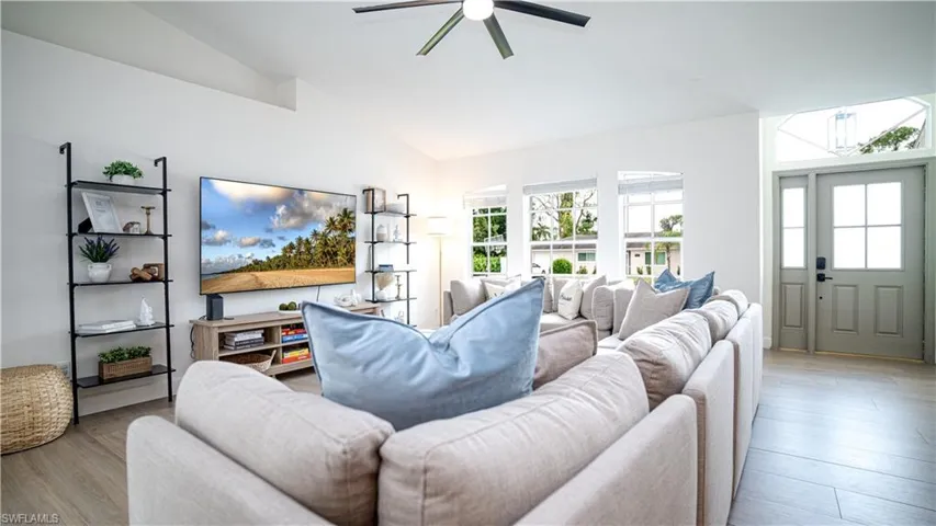 Living area with vaulted ceiling, wood finished floors, and ceiling fan