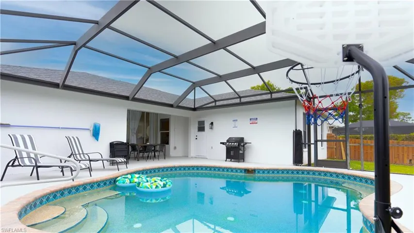 Outdoor pool featuring glass enclosure, a sunroom, area for grilling, and a patio area