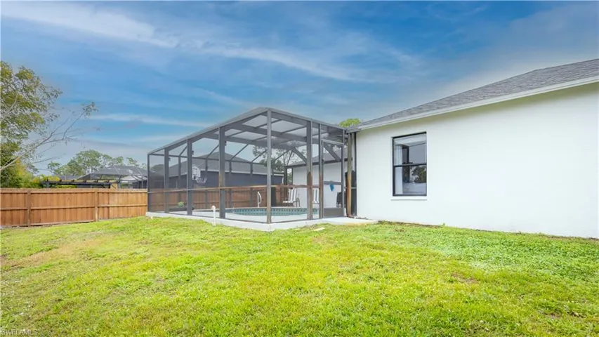 Back of house featuring a lanai, a sunroom, a fenced backyard, stucco siding, and a shingled roof