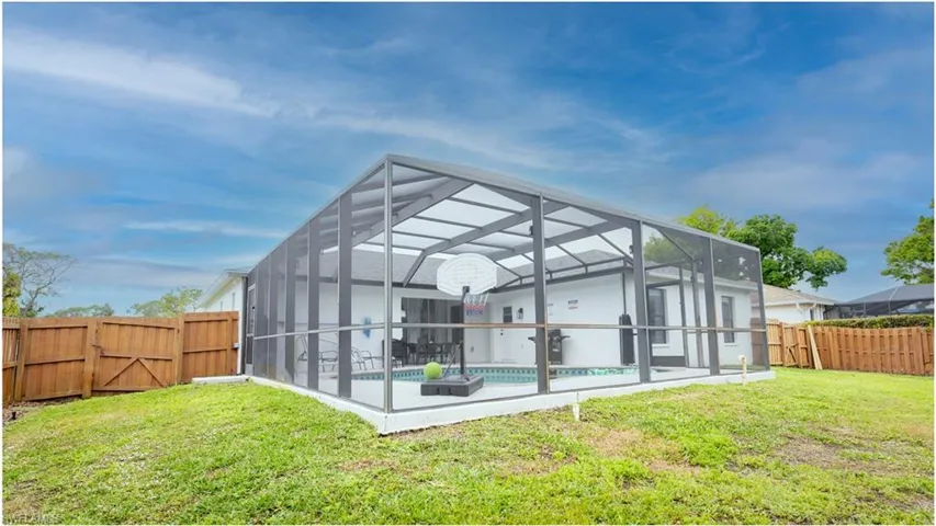 Rear view of property featuring a fenced backyard, a gate, a lanai, and a sunroom