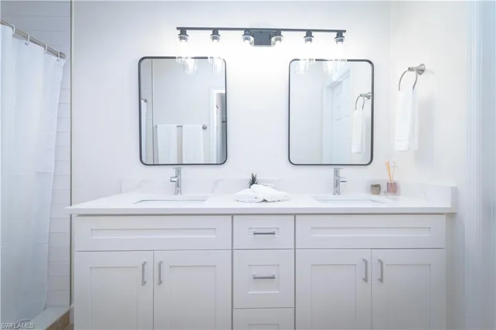 Full bath featuring double vanity and a shower with shower curtain