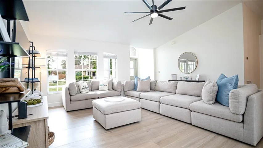 Living area with light wood-type flooring, high vaulted ceiling, and a ceiling fan