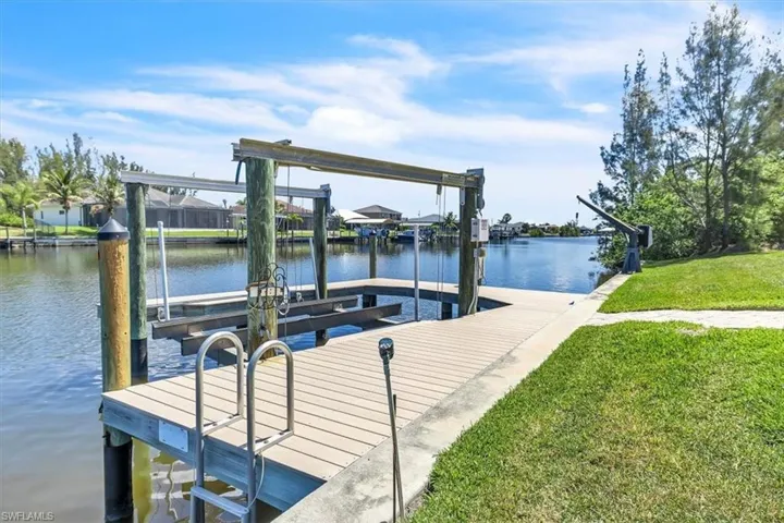 Waterfront property featuring a private boat dock with lift, stainless steel ladder, and a dedicated davit