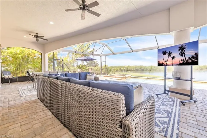 Expansive screened-in lanai featuring paver flooring, multiple ceiling fans, and arched openings