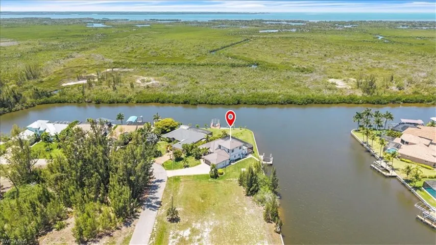 Waterfront property featuring a private boat dock, lush green landscaping, and direct canal access