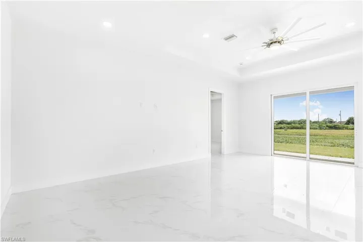 Unfurnished room with ceiling fan, light tile patterned floors, and a tray ceiling