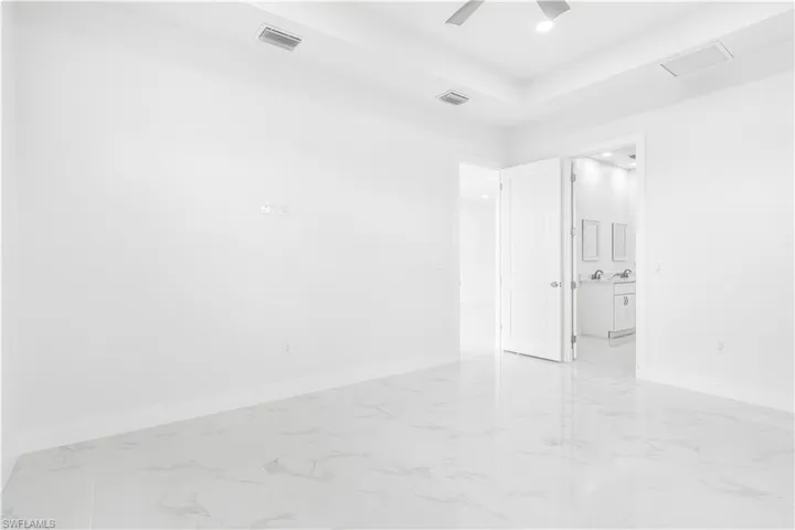 Tiled empty room with ceiling fan and a tray ceiling