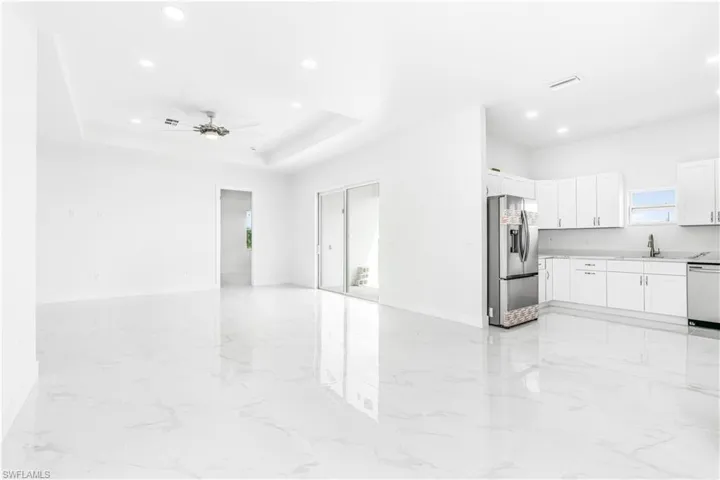 Living room with ceiling fan, sink, a raised ceiling, and light tile patterned floors