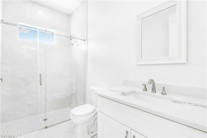 Bathroom featuring walk in shower, vanity, and toilet