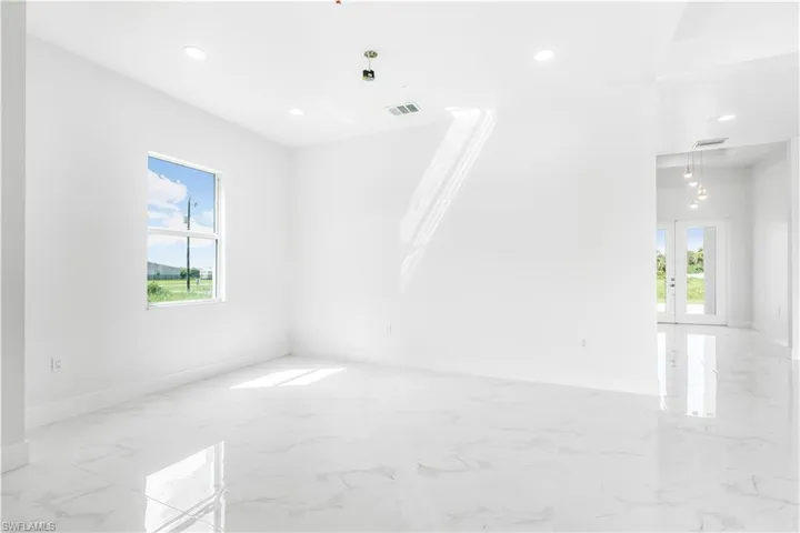 Empty room with french doors, light tile patterned floors, and a wealth of natural light