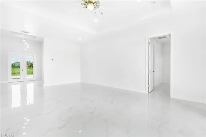 Spare room with light tile patterned flooring, french doors, ceiling fan, and a raised ceiling