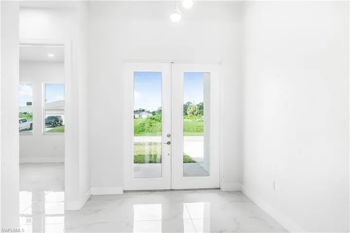 Doorway with french doors, light tile patterned floors, and a wealth of natural light