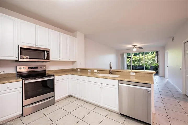 Kitchen featuring sink, white cabinets, light tile patterned floors, kitchen peninsula, and stainless steel appliances