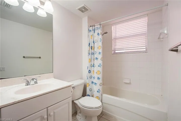 Full bathroom with shower / tub combo with curtain, vanity, toilet, and tile patterned floors