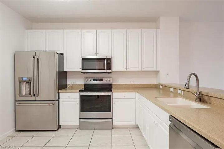 Kitchen with white cabinetry, appliances with stainless steel finishes, sink, and light tile patterned flooring