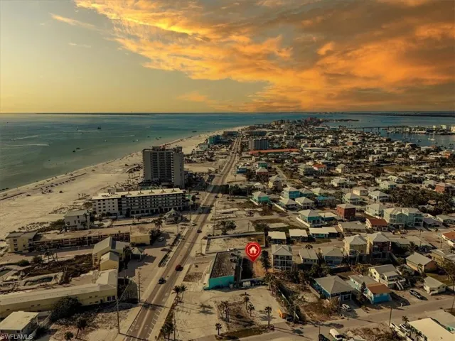 Aerial view at dusk featuring a water view and a beach view