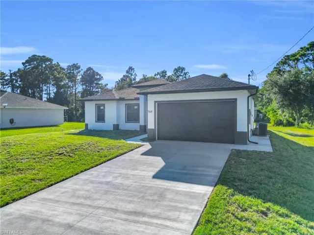 View of front of house featuring a front lawn, stucco siding, and driveway