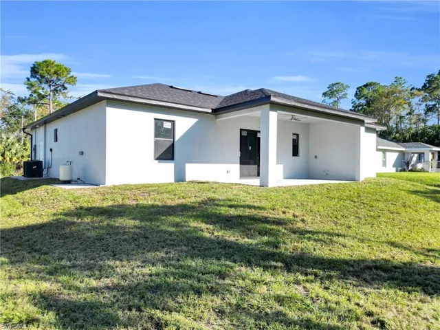 Back of house with a patio, a lawn, and stucco siding