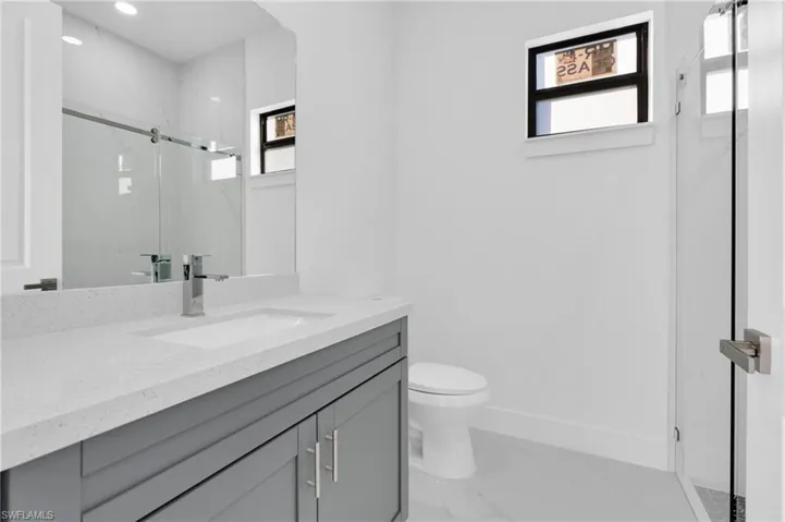 Bathroom featuring vanity and a marble finish shower