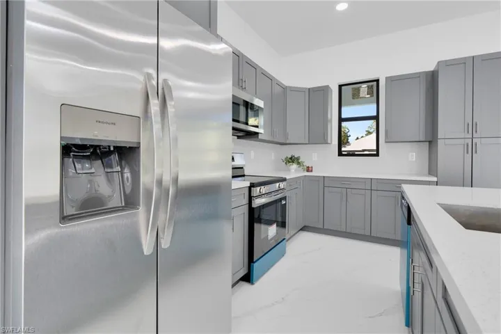 Kitchen with appliances with stainless steel finishes, light marble finish flooring, gray cabinetry, light stone countertops, and recessed lighting