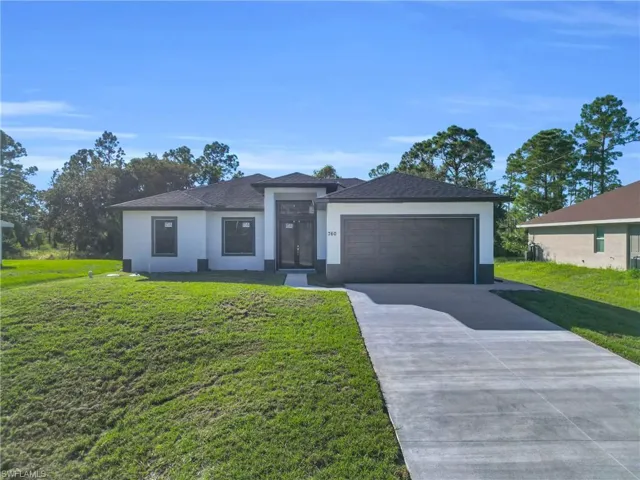 Prairie-style home with stucco siding, a front yard, and concrete driveway