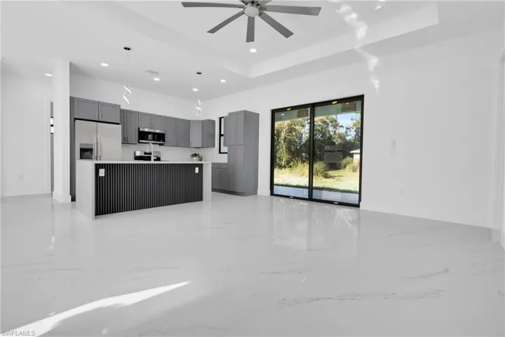 Kitchen featuring light marble finish floors, open floor plan, gray cabinets, a center island, and light countertops