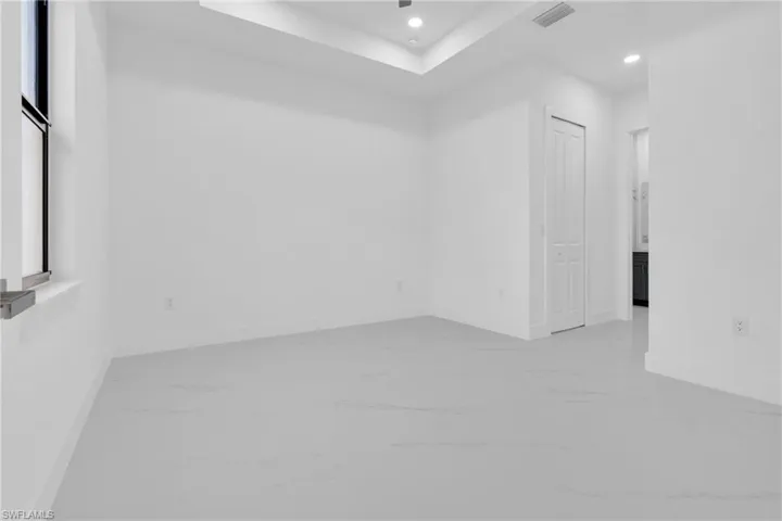 Spare room with recessed lighting, a raised ceiling, and light marble finish flooring