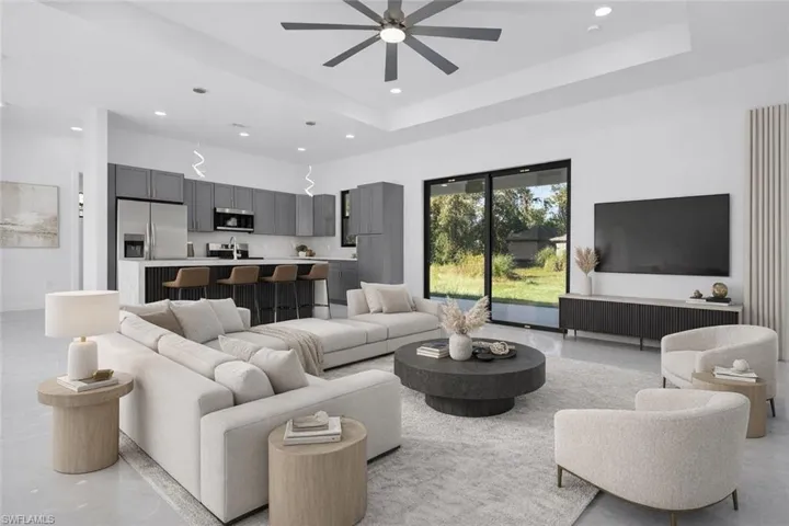 Living room featuring ceiling fan, a raised ceiling, and recessed lighting