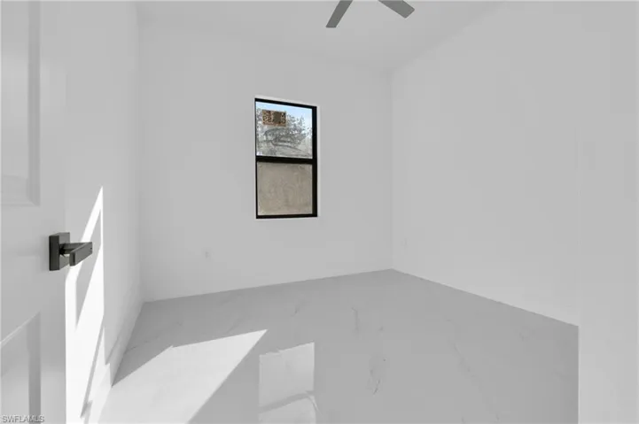 Empty room featuring marble look tile flooring and ceiling fan
