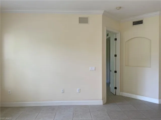Unfurnished room with crown molding and light tile patterned floors