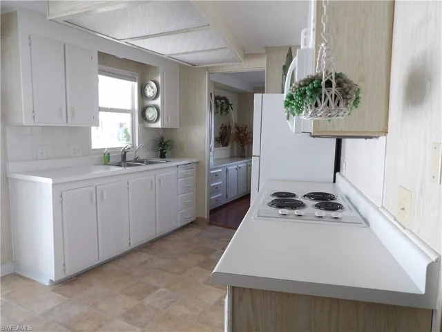 Kitchen with light countertops, tasteful backsplash, freestanding refrigerator, and white cabinets