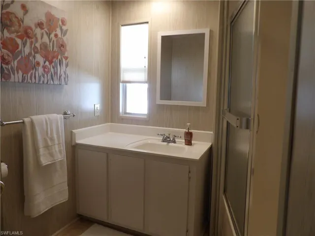 Bathroom featuring vanity, a stall shower, and wallpapered walls