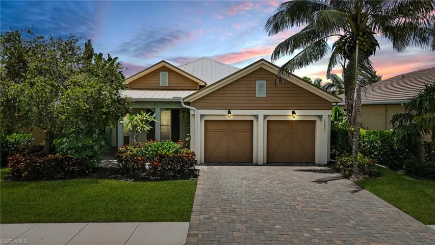 View of front of house featuring an attached garage, a front lawn, decorative driveway, and a metal roof