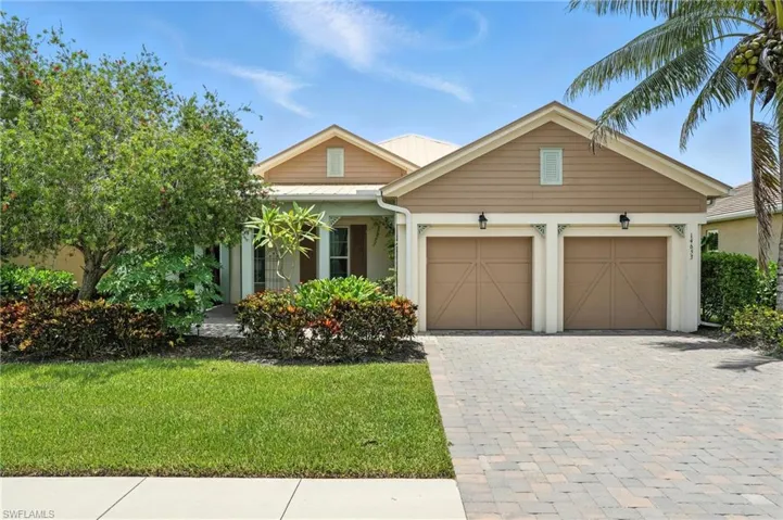 View of front of property with a garage, decorative driveway, a front yard, and a metal roof