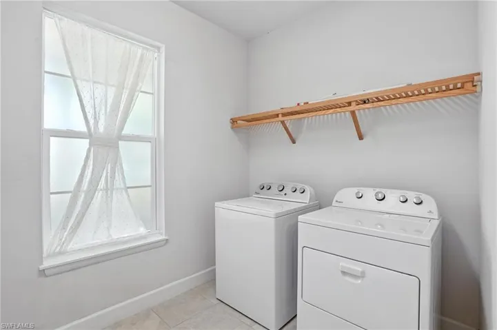 Laundry room with washing machine and clothes dryer and light tile patterned floors