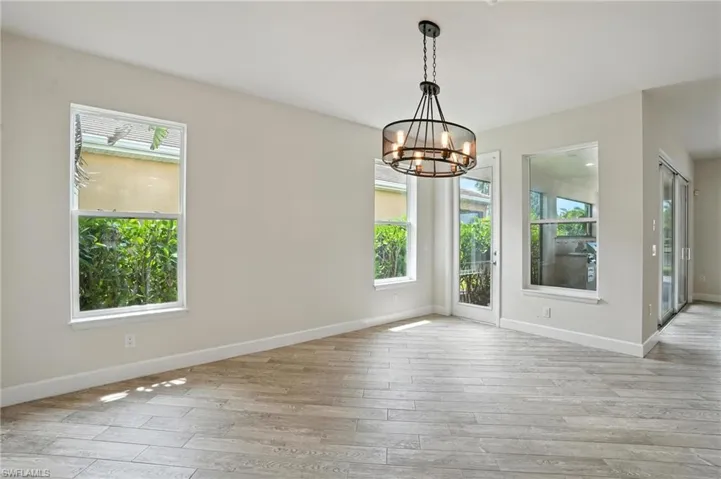 Spare room featuring plenty of natural light, a chandelier, and wood finished floors