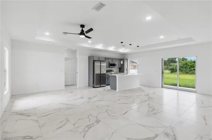 Unfurnished living room with a tray ceiling and ceiling fan
