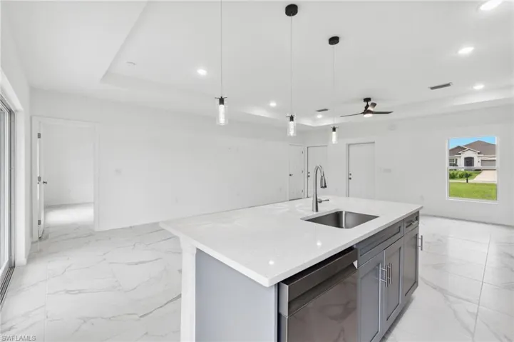 Kitchen with dishwasher, sink, ceiling fan, pendant lighting, and a center island with sink