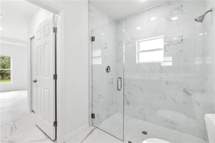 Bathroom featuring toilet and a shower with door