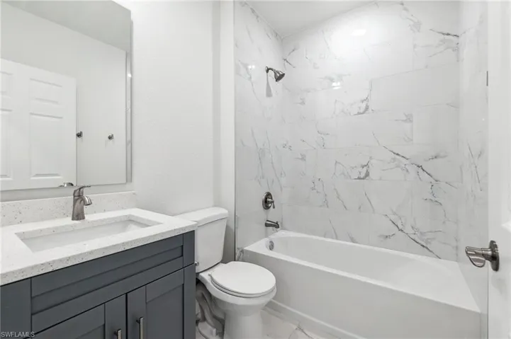 Full bathroom featuring tiled shower / bath, vanity, and toilet